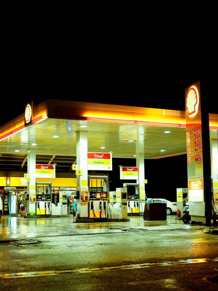 Brightly lit Shell gas station scene captured at night with clear visual of gas pumps and signage.