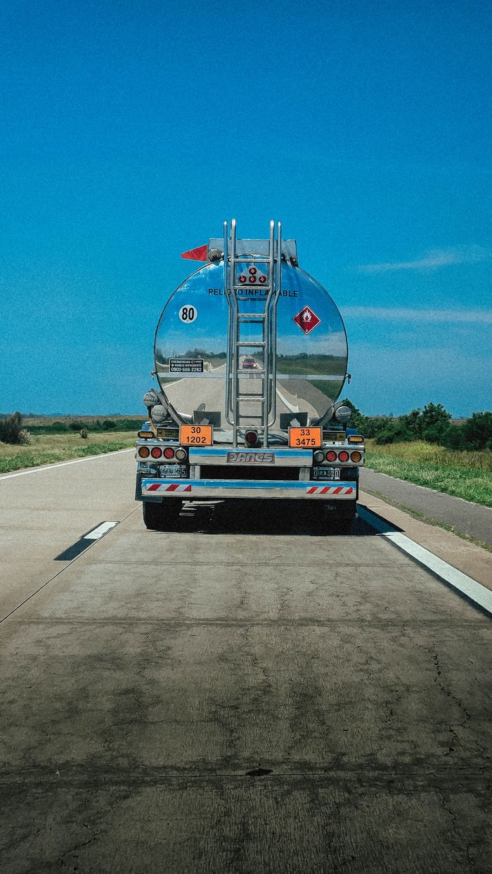 A fuel tanker truck travels along a highway under clear blue skies in Argentina.